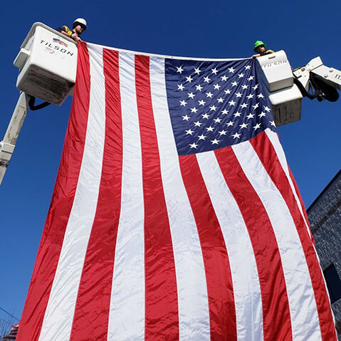 Large American flag hanging bucket trucks